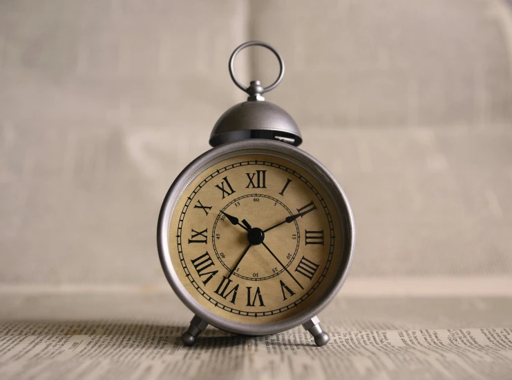 an alarm clock sitting on top of a table, by Romain brook, pexels, baroque, slightly tanned, mini model, circular, grey