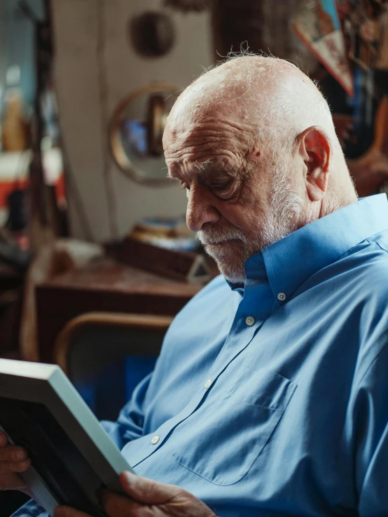 a man sitting in a chair reading a book, a portrait, pexels contest winner, portrait of hide the pain harold, in a workshop, profile image, ( ( theatrical ) )