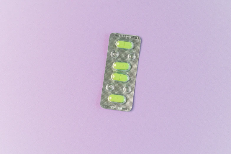 a pill pack sitting on top of a purple surface, by Amelia Peláez, trending on pexels, antipodeans, pale green glow, bedazzled, it has six thrusters in the back, fluorescent light