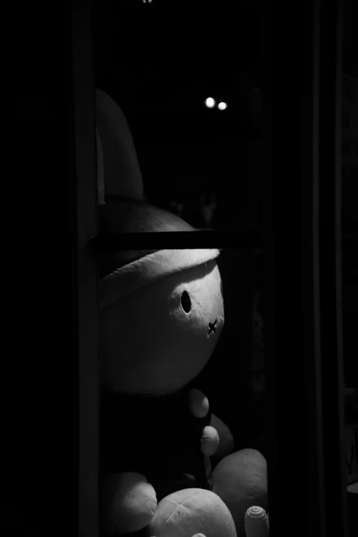 a black and white photo of a teddy bear in a window, a black and white photo, inspired by Jean Tabaud, unsplash, stay puft marshmallow man, in a dark dungeon, character with a hat, hollow knight