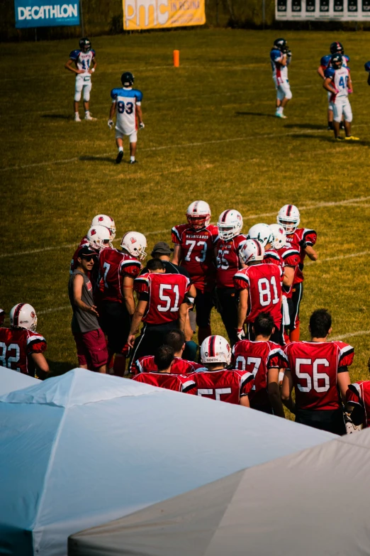 a group of football players standing on top of a field, by Arnie Swekel, pexels contest winner, white and red armor, sumerville game, start of the match, shady look