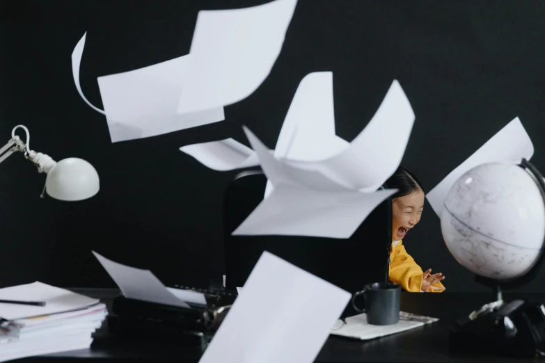 a person sitting at a desk with papers flying in the air, by Fei Danxu, pexels contest winner, conceptual art, medium shot of two characters, frustration, promo image, asian woman made from origami