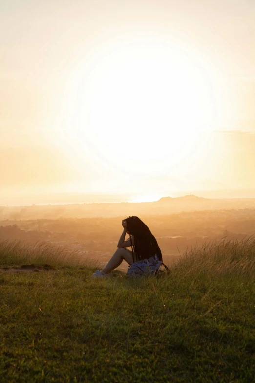 a woman sitting on top of a lush green field, by Julian Allen, trending on unsplash, romanticism, looking off into the sunset, looking sad, high quality photo, broken down