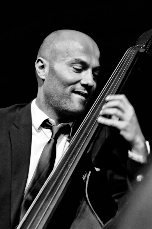 a man in a suit playing a double bass, smug smirk, bald, christophe szpajdel, simone graci