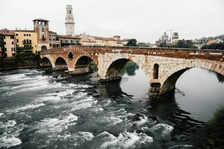 a bridge over a river with a clock tower in the background, inspired by Christo, pexels contest winner, renaissance, white stone arches, alessio albi, rapids, looking towards the camera