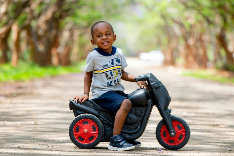 a little boy that is sitting on a toy motorcycle, inspired by Joze Ciuha, pexels contest winner, mongezi ncaphayi, mid length portrait photograph, mini model, thumbnail