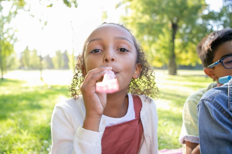 a couple of kids sitting on top of a lush green field, pexels contest winner, blowing bubblegum, light skinned african young girl, people outside eating meals, marshmallow