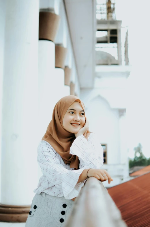 a woman wearing a hijab standing on a balcony, inspired by JoWOnder, pexels contest winner, hurufiyya, cute smile, white building, ((portrait)), simplistic