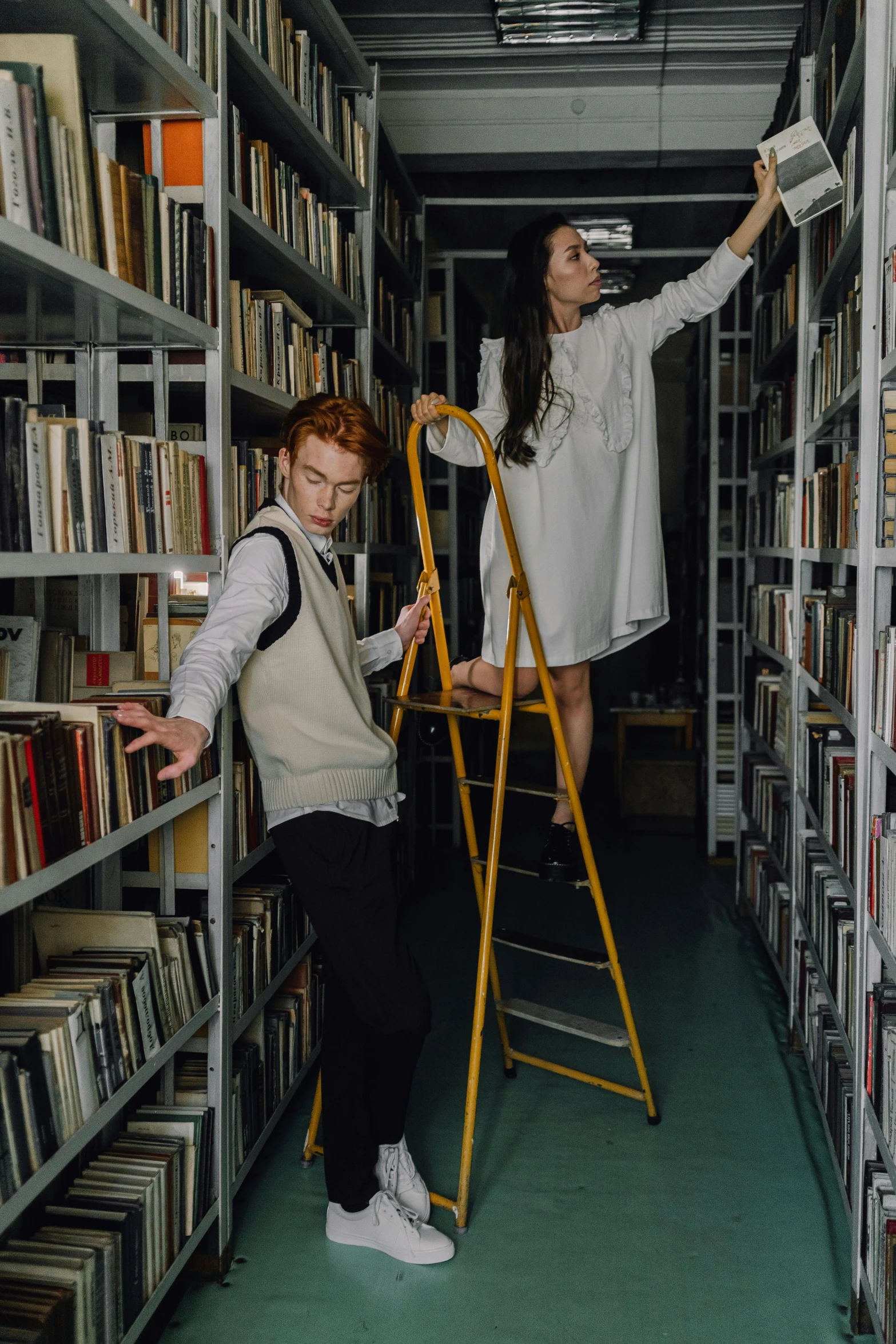 a couple of people standing on a ladder in a library, an album cover, by Everett Warner, unsplash, renaissance, grimes, sassy pose, ignant, 15081959 21121991 01012000 4k