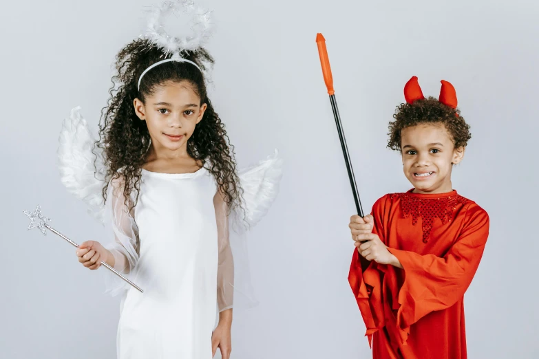 two little girls dressed up in halloween costumes, a cartoon, pexels contest winner, antipodeans, angel versus devil, mixed race, white and orange, with scepter and crown