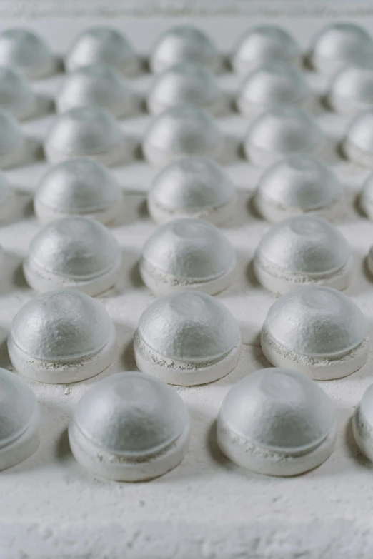 a close up of a tray of doughnuts on a table, inspired by Rachel Whiteread, unsplash, plasticien, many cryogenic pods, white metallic armour, in rows, wearing a white bathing cap