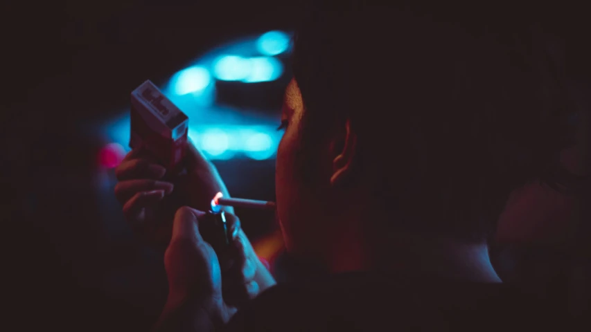 a person smoking a cigarette in the dark, inspired by Elsa Bleda, pexels contest winner, 8 0 s asian neon movie still, vhs colour photography, cold blue light, instagram picture