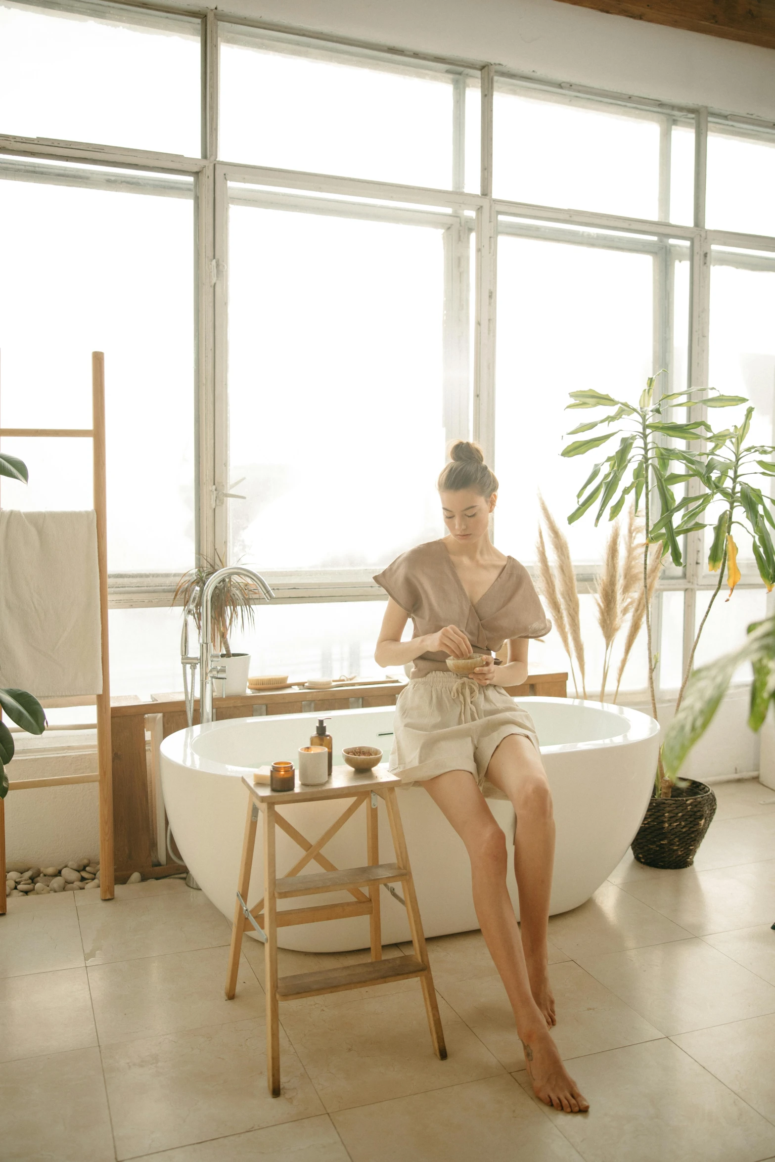 a woman sitting in a bath room next to a window, trending on pexels, sitting on a stool, botanicals, drinking, crisp clean shapes