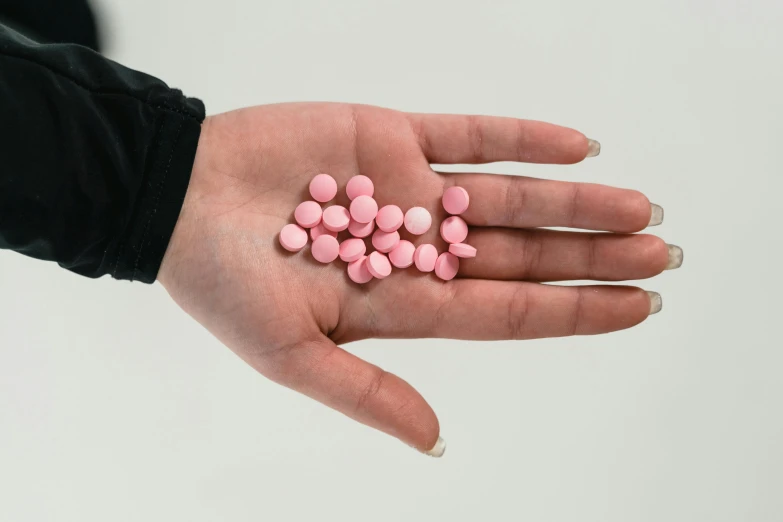 a person holding a handful of pink pills, by Nina Hamnett, antipodeans, flattened, 3 mm, bubblegum, male and female