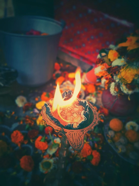 a lit candle surrounded by flowers on a table, samikshavad, flaming torches and pitchforks, promo image, multiple stories, temple