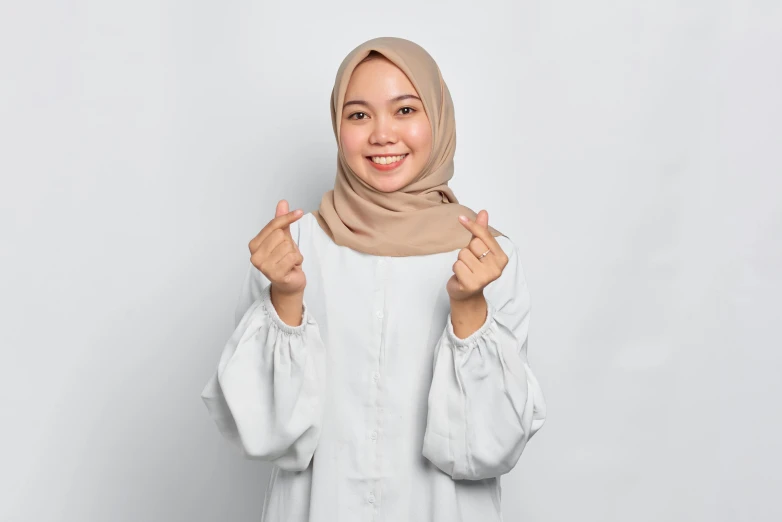 a woman wearing a hijab posing for the camera, pexels contest winner, dau-al-set, basic white background, beige, pose(arms up + happy), wikihow