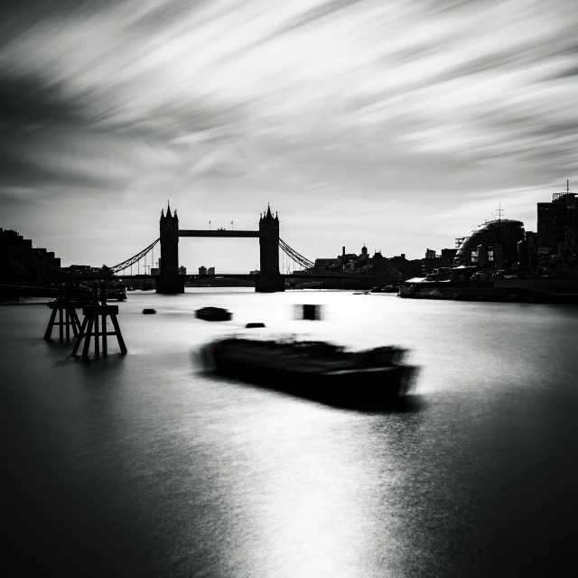 a boat in a body of water with a bridge in the background, a black and white photo, by John Hutton, pexels contest winner, speeding through london, medium format, by emmanuel lubezki, long exposure photo