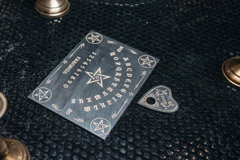 a book sitting on top of a black table, pentagram, pair of keycards on table, detail shot, black resin