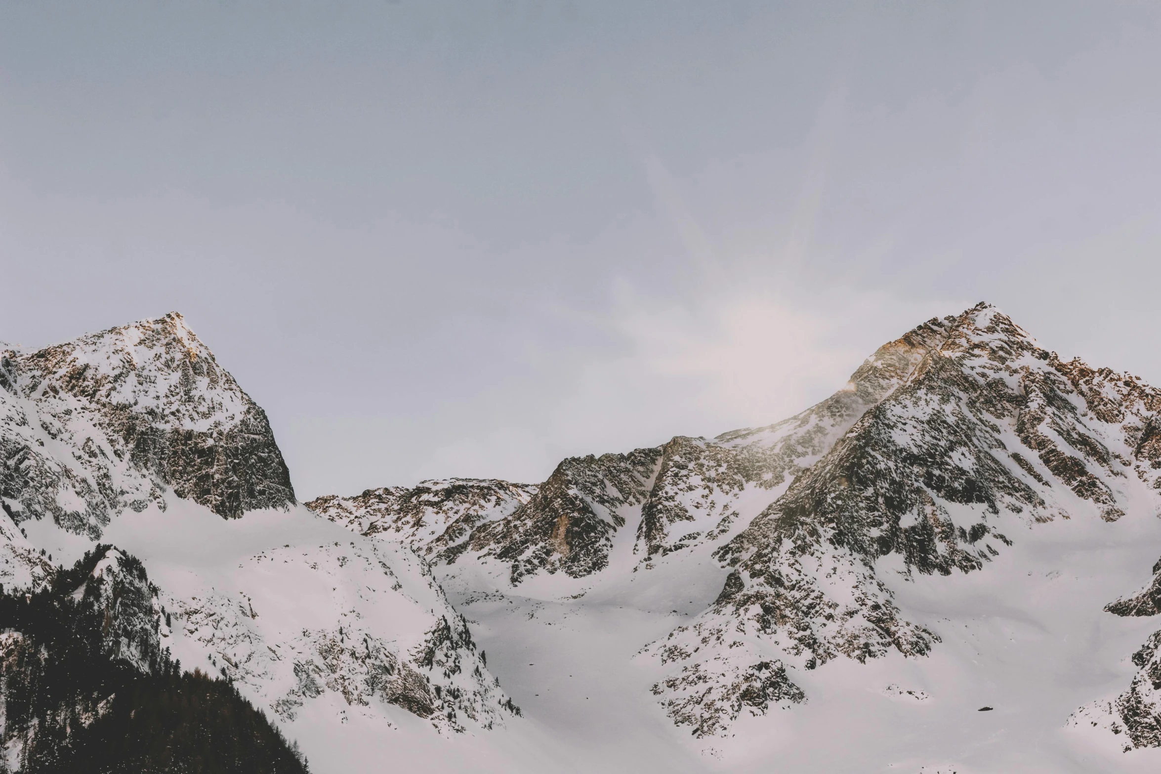 a group of people riding skis on top of a snow covered slope, a photo, pexels contest winner, minimalism, large rocky mountain, website banner, late afternoon light, the middle of a valley