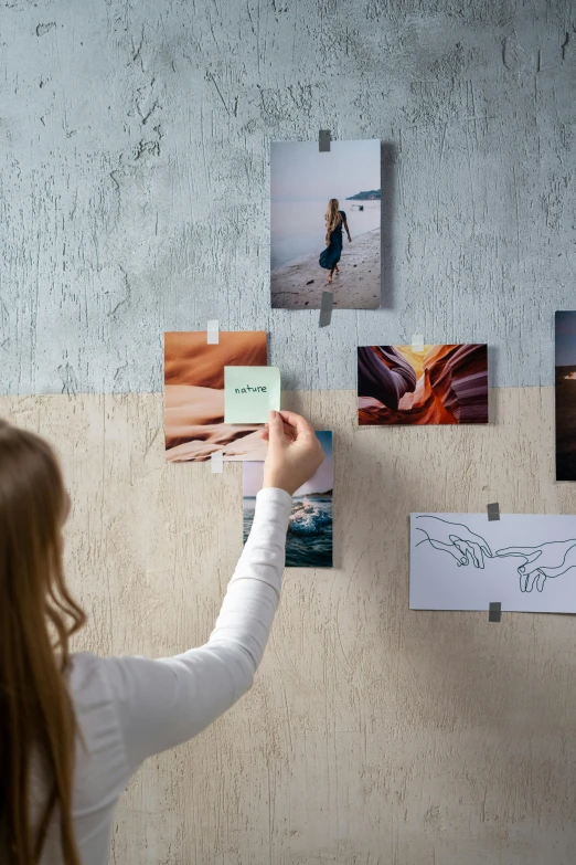 a woman is hanging pictures on a wall, inspired by Maud Naftel, trending on unsplash, storyboard, full color photograph, on high-quality paper, product introduction photo