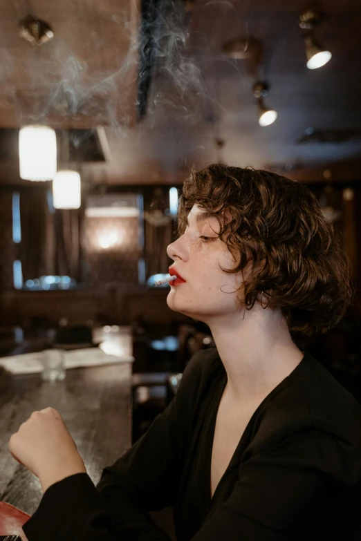 a woman sitting at a bar smoking a cigarette, a portrait, inspired by Nan Goldin, trending on unsplash, art nouveau, wavy short hair, high quality photo, finn wolfhard, fine background proportionate