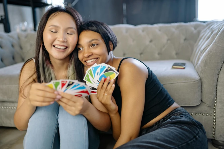 a couple of women sitting on top of a couch, pexels contest winner, trading card game, rainbow colored, half asian, teenage girl