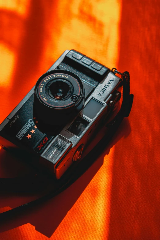 a camera sitting on top of an orange sheet, posing for a picture, frontal shot, front shot