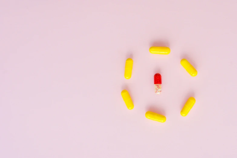 a group of yellow and red pills arranged in a circle, an album cover, by Nicolette Macnamara, trending on pexels, antipodeans, pink, tiny spaceship, ultra minimalistic, iu