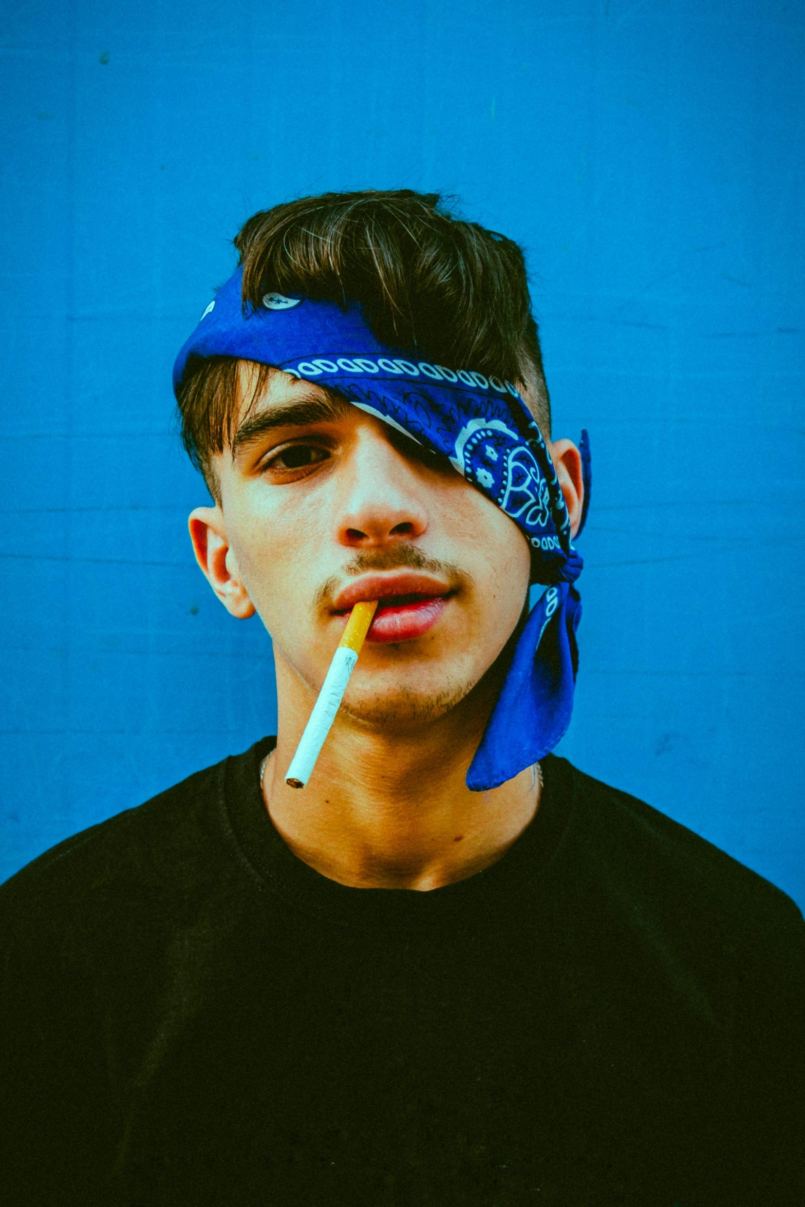 a man wearing a bandana with a cigarette in his mouth, an album cover, inspired by John Luke, trending on pexels, blue mood, bad boy, discord pfp, ariel perez