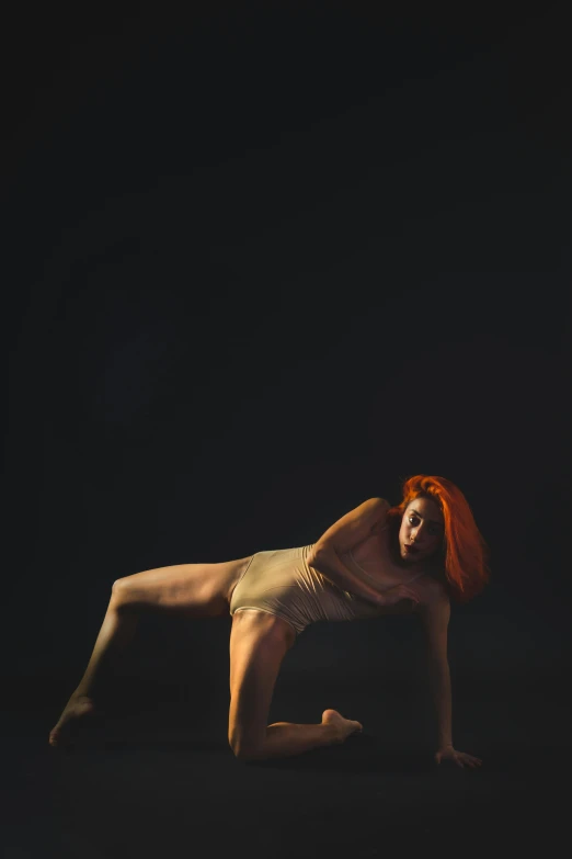 a woman doing a yoga pose against a black background, by Elizabeth Polunin, woman with red hair, studio medium format photograph, ochre, show