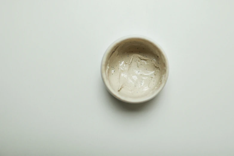 a white bowl sitting on top of a table, a stipple, by Emily Shanks, process art, skincare, cream, beige, facemask