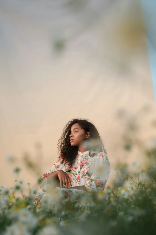 a woman sitting in a field of flowers, a picture, by Winona Nelson, pexels contest winner, black young woman, in front of white back drop, evening lighting, complex background