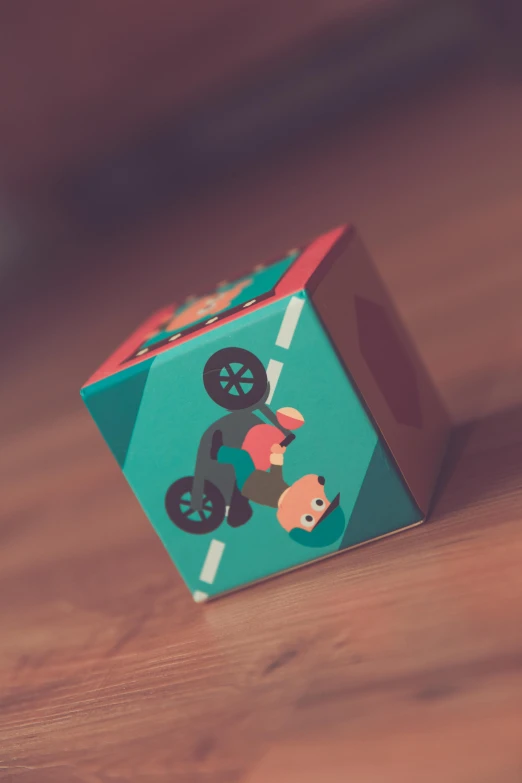 a toy sitting on top of a wooden table, inspired by Emiliano Ponzi, unsplash, cubo-futurism, biker, teal paper, avatar image, drifting around a corner