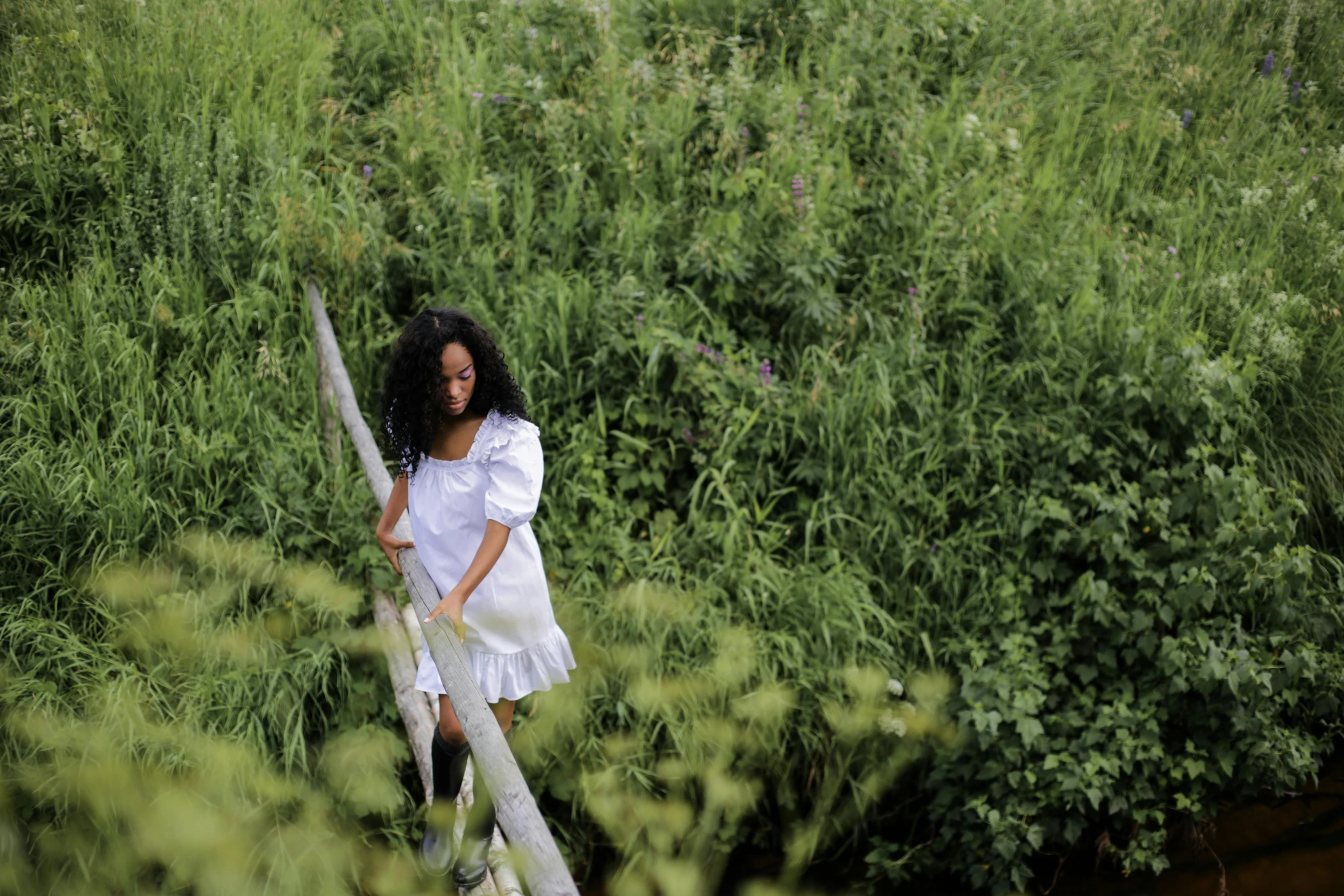 a woman in a white dress walking across a bridge, a portrait, inspired by Andrew Wyeth, pexels contest winner, with afro, standing in tall grass, standing on a ladder, sza