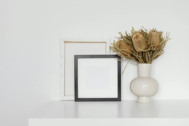 a white table topped with a vase filled with dried flowers, a black and white photo, visual art, background image, square pictureframes, product image, small