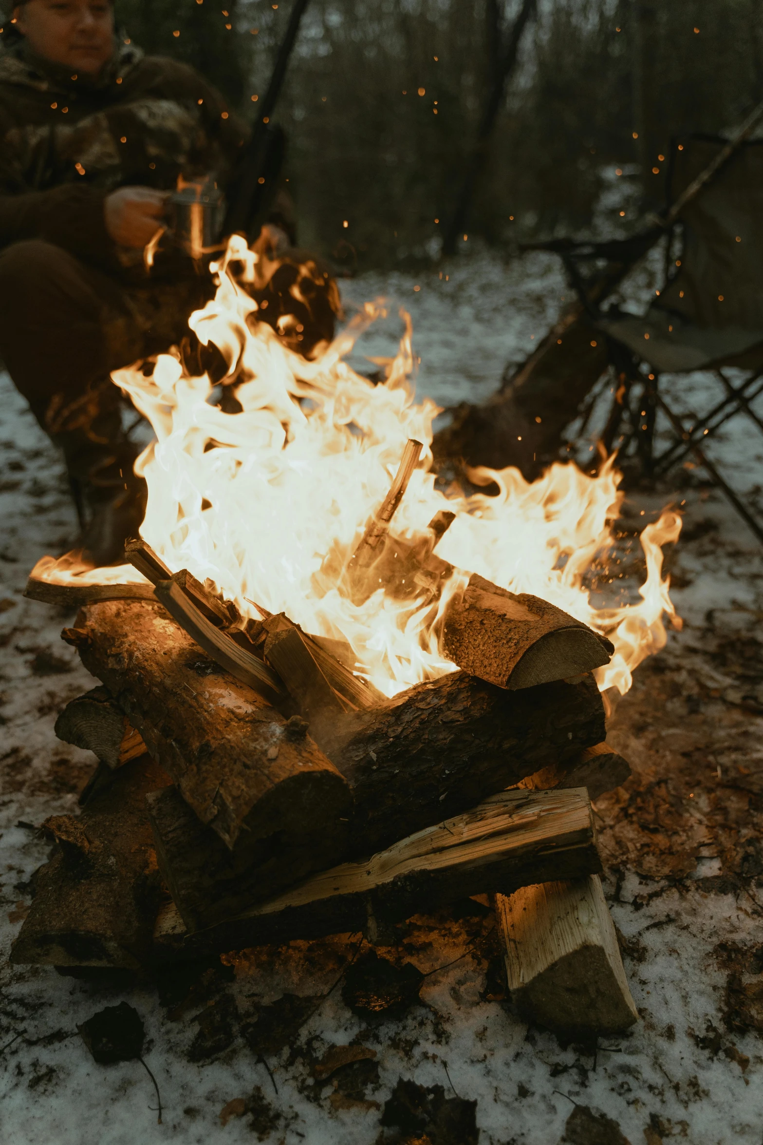 a man sitting next to a fire in the snow, pexels contest winner, renaissance, at a campfire in the forest, wood burn, birch, dancing around a fire