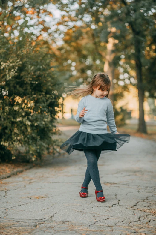 a little girl is walking down a path, pexels contest winner, arabesque, classic dancer striking a pose, tights, grey, wearing casual clothing