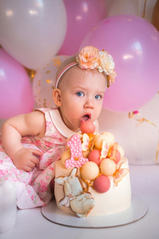 a baby girl sitting in front of a birthday cake, a portrait, by Tom Bonson, pexels, baroque, baloons, looking towards camera, covered with pink marzipan, just