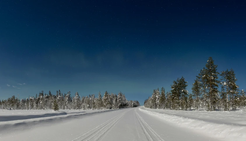 a person riding skis down a snow covered slope, by Veikko Törmänen, hurufiyya, moonlit parking lot, blue clear skies, road in a forest road, thumbnail