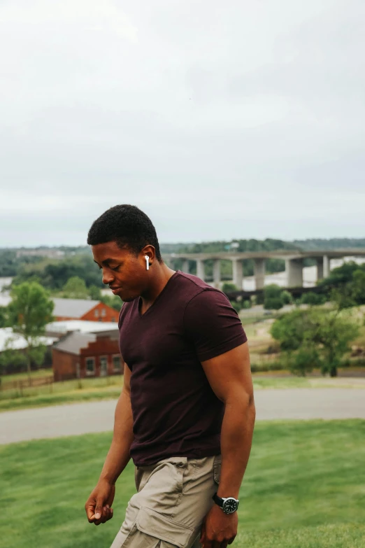 a man riding a skateboard on top of a lush green field, an album cover, by Stokely Webster, unsplash, standing in a township street, wearing purple undershirt, thoughtful pose, looking over city