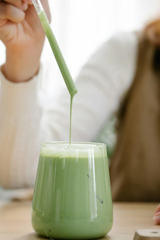 a person pouring green liquid into a cup, inspired by Kanō Tan'yū, trending on pexels, drink milkshakes together, profile image, made of glazed, woman