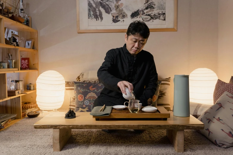 a man sitting on top of a wooden table, inspired by Sesshū Tōyō, trending on unsplash, shin hanga, tea drinking and paper lanterns, traditional korean interior, production photo, youtube thumbnail