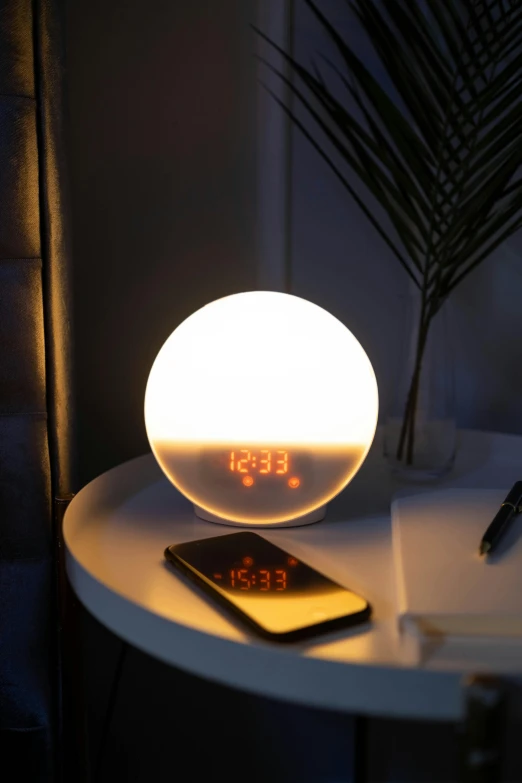 a clock sitting on top of a table next to a cell phone, by Évariste Vital Luminais, ambient amber light, spherical, warm bright white light, multicoloured