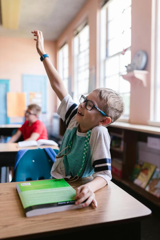 a young boy sitting at a desk in a classroom, by Andrew Domachowski, pexels contest winner, waving arms, blippi, blake stone, in an action pose