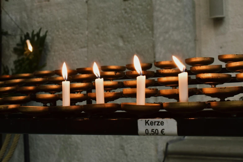 a group of lit candles sitting on top of a table, inspired by Károly Markó the Elder, chartres cathedral, krenz, symbol for the word ersatz, on a candle holder