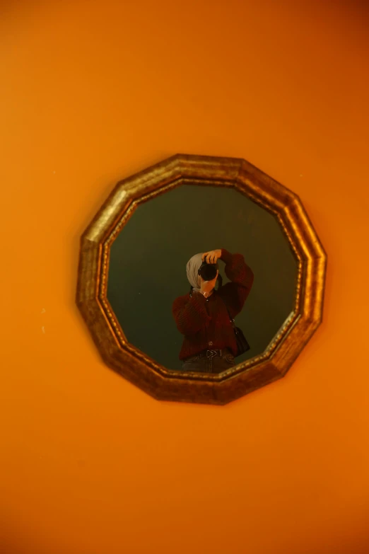 a close up of a mirror on a wall, an album cover, inspired by Georges de La Tour, conceptual art, orange halo, self - portrait, gold framed, xqc