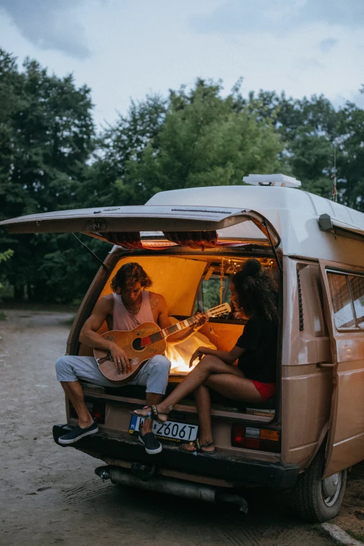 a group of people sitting in the back of a van, pexels contest winner, renaissance, playing a guitar, romantic couple, cabin lights, 🚿🗝📝