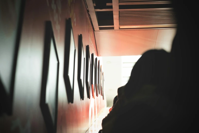 a person standing in a hallway next to a wall, visual art, crowded silhouettes, facing away from camera, instagram post, capsule hotel