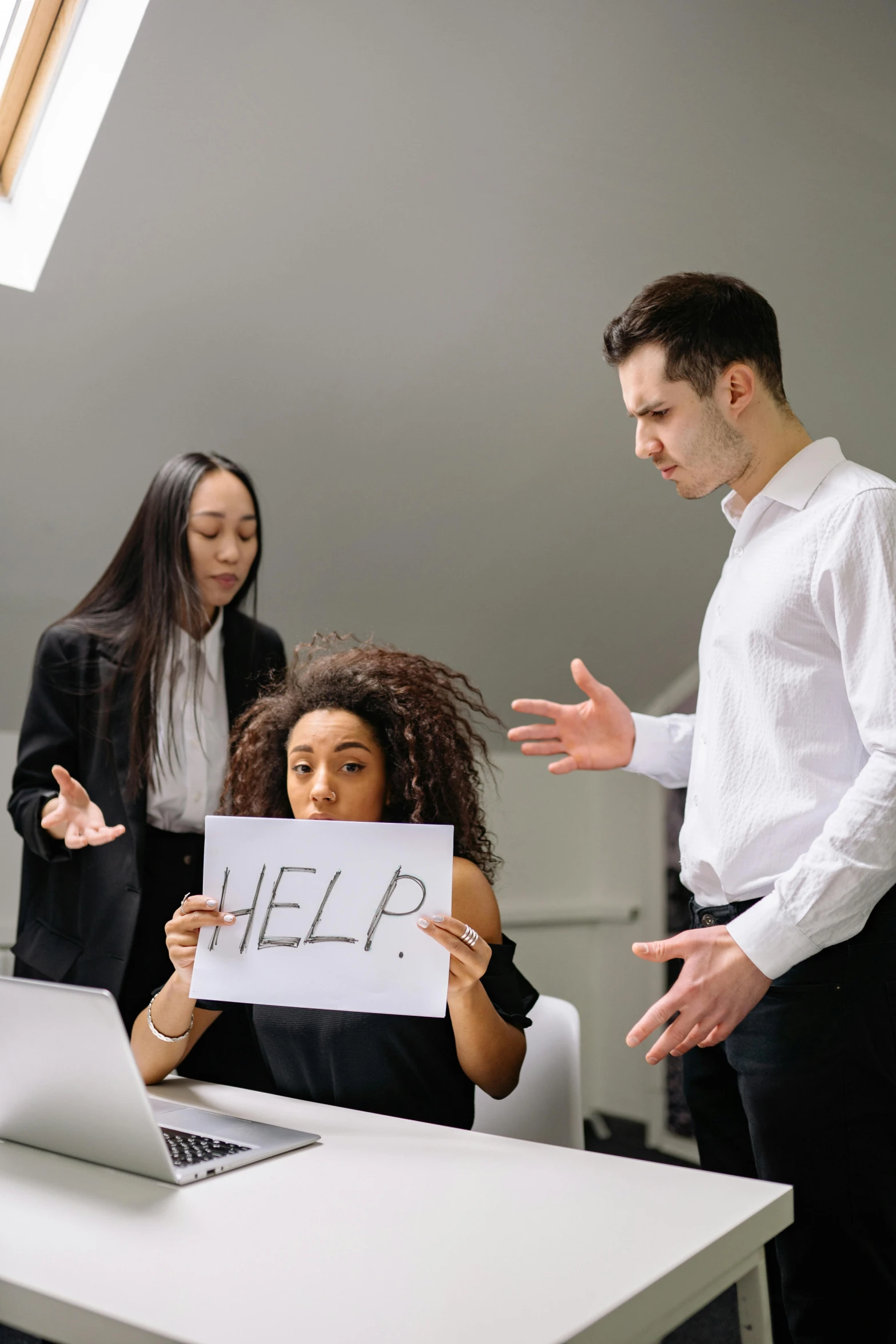 a group of people standing around a table holding a sign, pexels, frustrated, it specialist, sitting on a desk, high quality picture