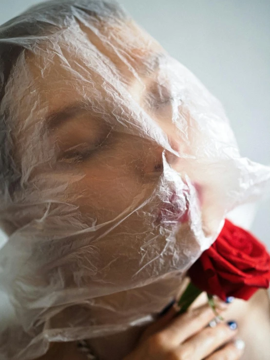 a woman covering her face with a plastic bag, an album cover, inspired by Méret Oppenheim, trending on unsplash, roses, ignant, covered in bandages, profile image